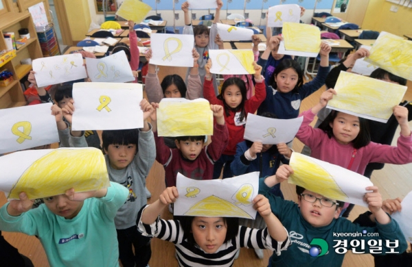 세월호참사 5주기를 하루 앞둔 15일 용인시 한얼초등학교 3학년 2반 학생들이 참사 희생자들을 추모하며 노란리본과 세월호를 상징하는 배를 그린 뒤 펼쳐보이고 있다. /김금보 기자