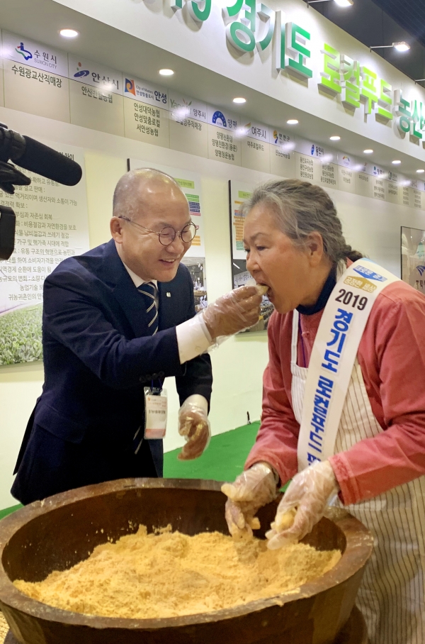 강위원 경기농식품유통진흥원장이 지난 11월20일 서울 코엑스에서 열린 ‘2019 경기도 로컬푸드 농축산물 대축제’에 참석, 행사 직원에게 시식용 떡을 권유하고 있다.