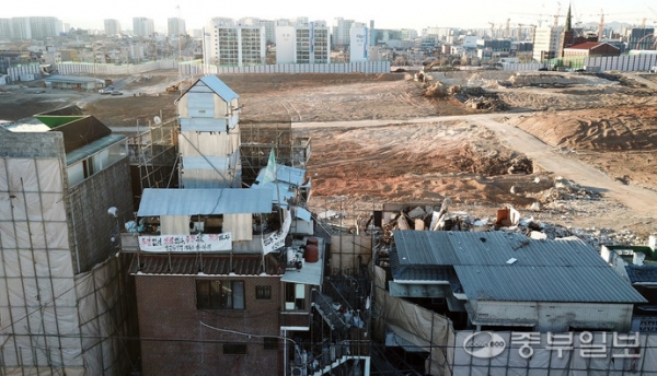 권선113-6구역재개발사업 공사현장과 재개발보상금 증액을 요구하며 이주를 거부하는 한 건물 소유주가 본인의 건물에 망루를 설치한 모습. 사진=노민규기자