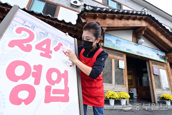 단계적 일상회복(위드 코로나) 시행을 하루 앞둔 31일 오후 수원시 한 음식점에서 관계자가 24시 영업 간판을 닦고 있다. 노민규기자