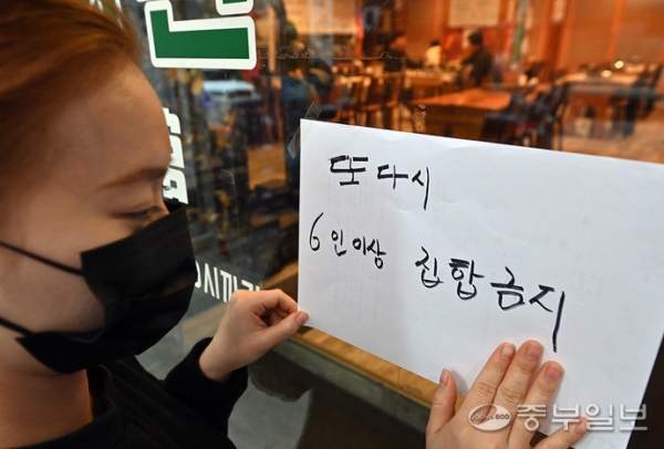 정부가 일상회복 시작 이후 빠르게 확산하고 있는 코로나19 유행을 통제하기 위해 6일부터 4주 동안 사적모임 최대 인원을 수도권 6명으로 제한하기로 발표한 가운데 5일 오후 수원시 한 음식점에서 종업원이 집합금지 안내문을 붙이고 있다. 노민규기자