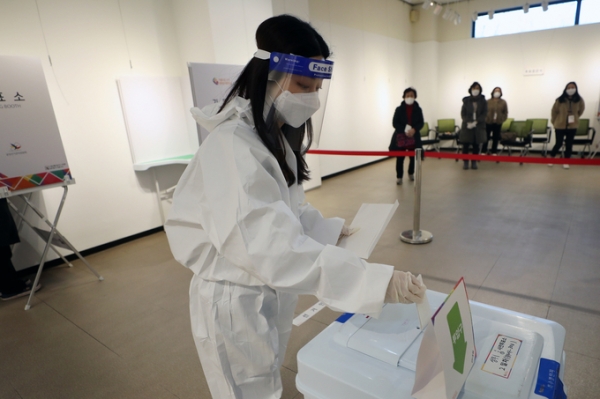 ▲ 제20대 대통령선거 사전 투표 이틀째인 5일 오후 광주 서구 학생교육문화회관에 마련된 상무1동 사전투표소에서 확진·격리자들이 투표한 투표용지를 방역복을 입은 관계자가 전달받아 투표함에 넣고 있다. (사진=연합뉴스 제공)