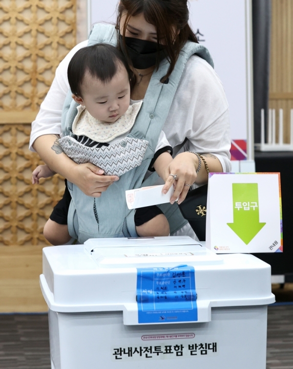 ▲ 6·1 지방선거 사전 투표일인 28일 오후 수원시청 별관에 마련된 투표소에서 한 유권자가 아이와 함께 기표용지를 투표함에 넣고 있다. /김철빈 기자