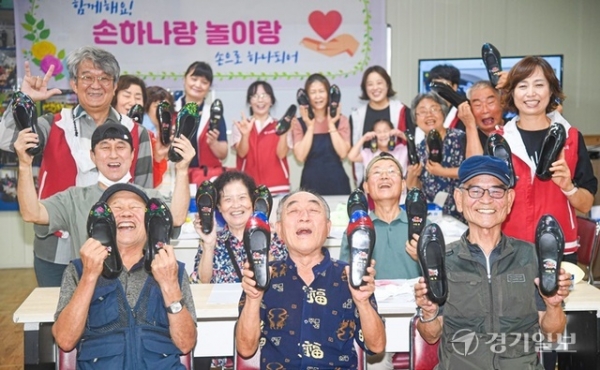웃음소리는 없지만, 웃음꽃이 활짝 피었다. 수어봉사동아리 ‘손으로 하나되어’ 회원과 농아 어르신들이 수원시농아인쉼터에서 함께 만든 꽃신을 들어보이며 환하게 웃고 있다. 조주현 기자