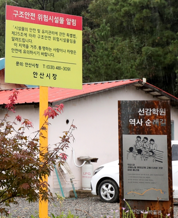 ▲ 지난 3일 안산시 단원구 옛 선감학원 아동집단시설 건물에 거주하고 있는 한 주민 집 앞에 '구조안전 위험물 알림' 표지판이 설치되어 있다. 뒤로 가정용 LP 가스통과 승용차가 보이고 있다./김철빈 기자