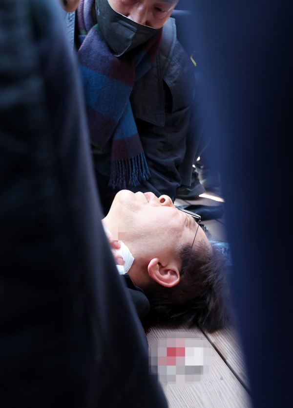 ▲ 더불어민주당 이재명 대표가 2일 오전 부산 가덕도 신공항 부지를 둘러본 후 기자들과 문답을 진행하던 중 왼쪽 목 부위에 습격을 당해 피를 흘린 채 쓰러져 있다. /연합뉴스