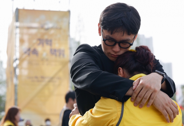 ▲ 16일 오후 화랑유원지 앞 한 추모객이 유가족을 위로하고 있다. (사진=옥지훈 기자)