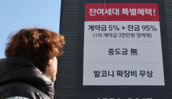 한 시민이 경기도 고양시 한 부지에 세워진 분양 아파트 견본주택 홍보물을 바라보고 있다. (사진=연합뉴스 제공)