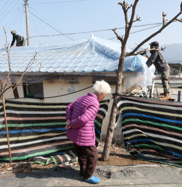 11일 오전 포천시 이동면 노곡리 공군 전투기 민가 오폭 사고 현장에서 주택 피해를 입은 할머니가 지붕 수리를 돕는 군인들을 바라보며 자리를 옮기고 있다./김철빈 기자